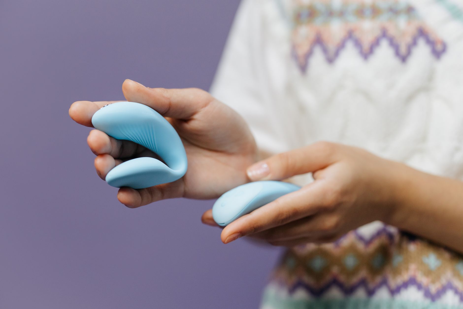 Close-up of hands holding a sleek blue vibrator, representing intimate connection for busy couples