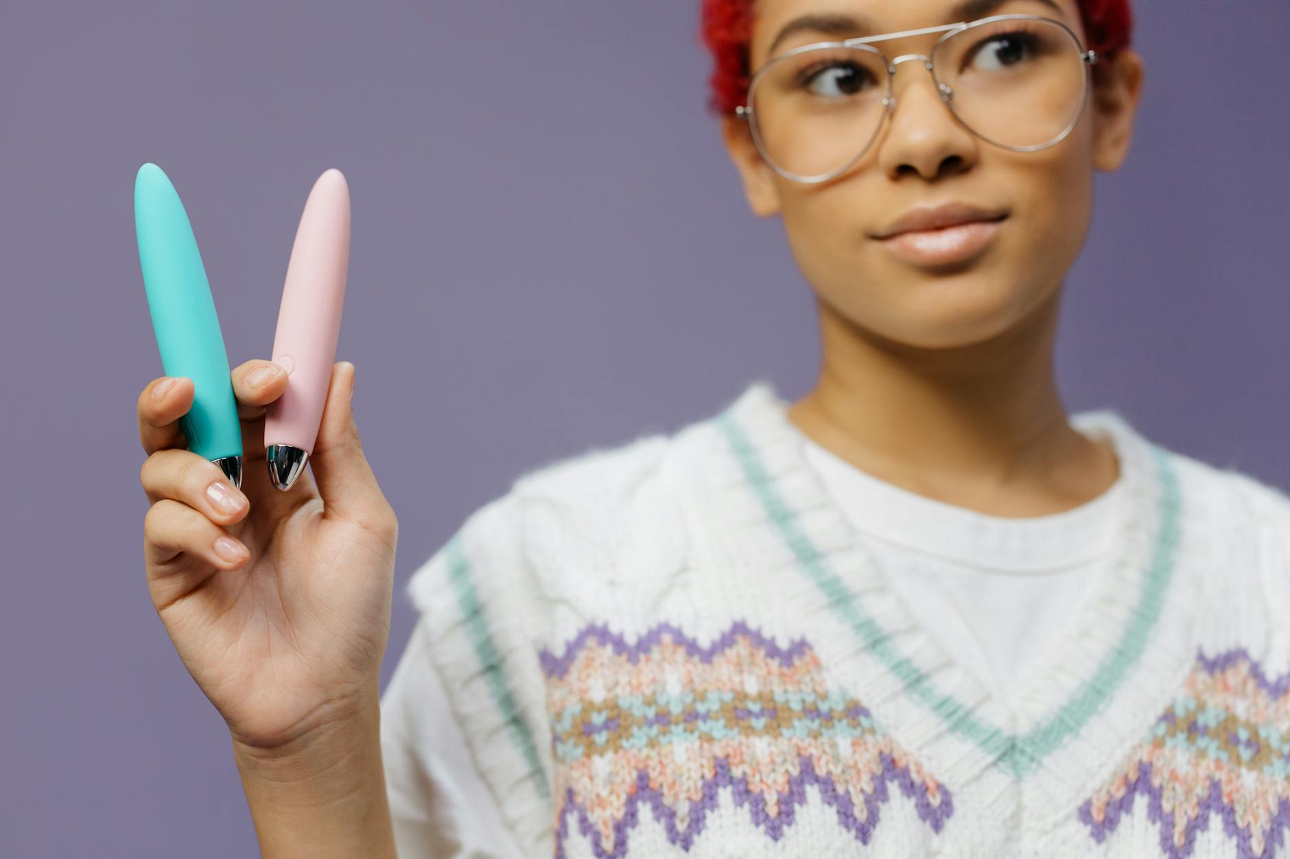 Two colorful vibrators held together against a purple background, representing pleasure and choice