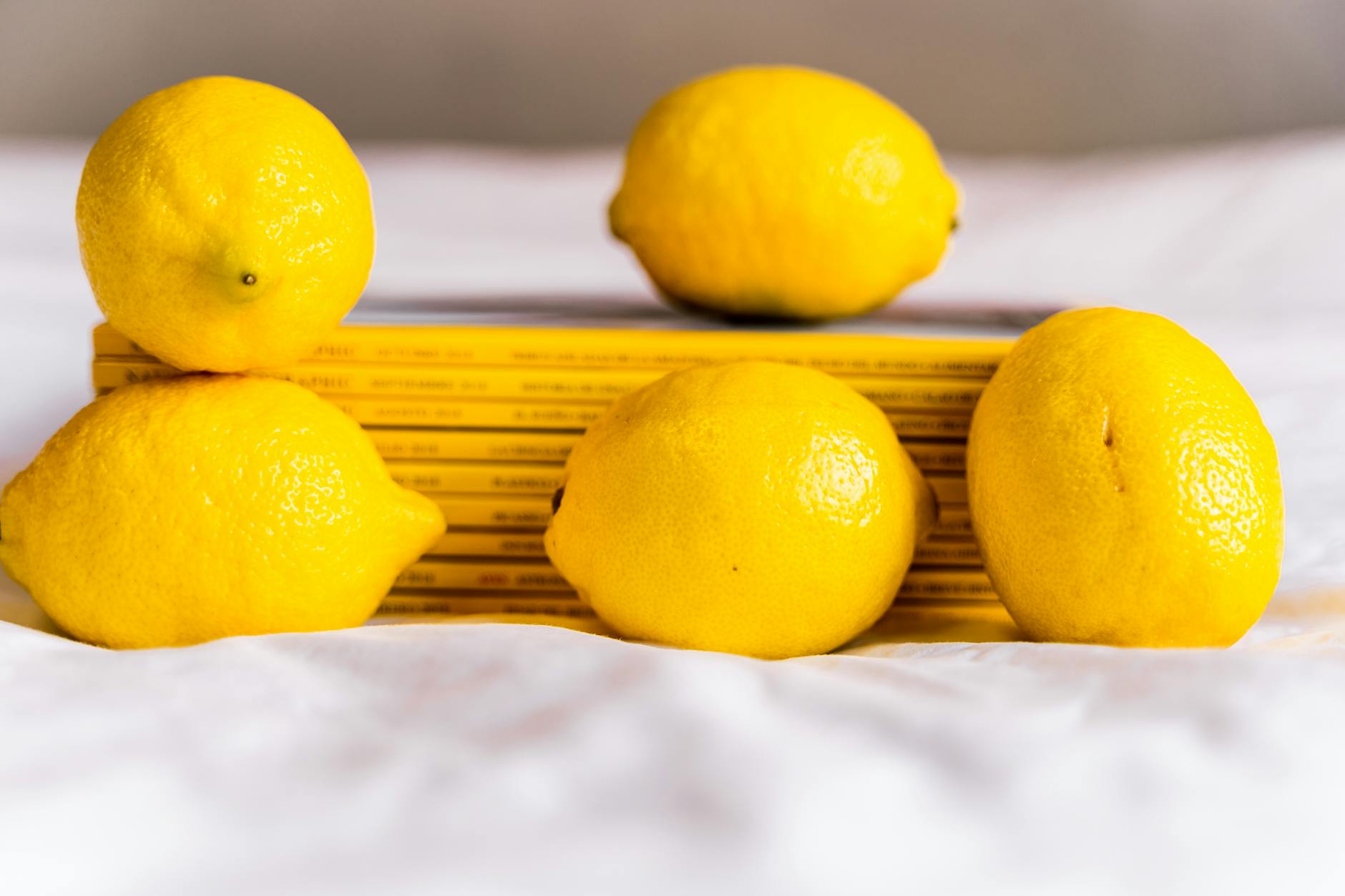 Fresh yellow lemons arranged with stacked books on a white surface, symbolizing portable joy and travel